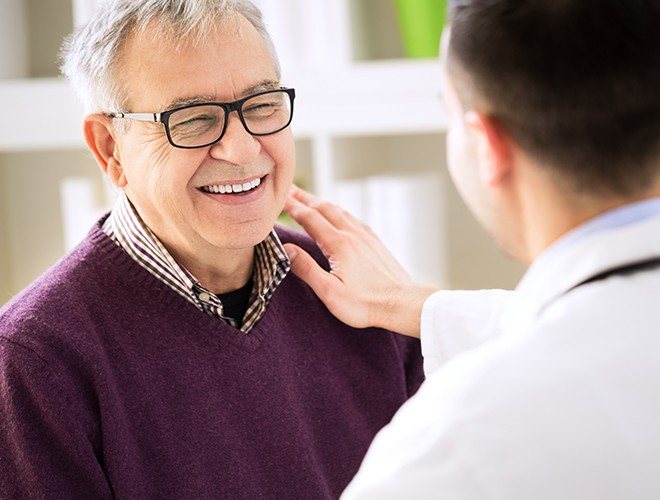 Older man smiling at dentist during restorative dentistry appointment