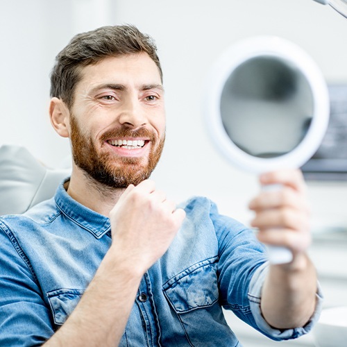 Man looking at his smile after one visit dental restoration placement