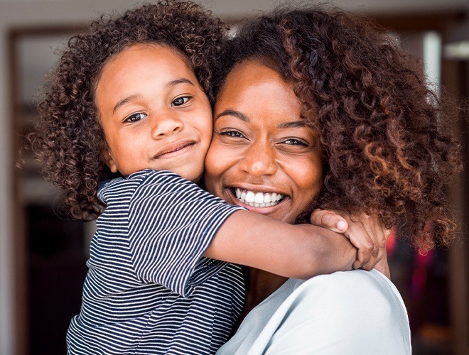 Mother holding child who has a healthy smile thanks to children's dentistry