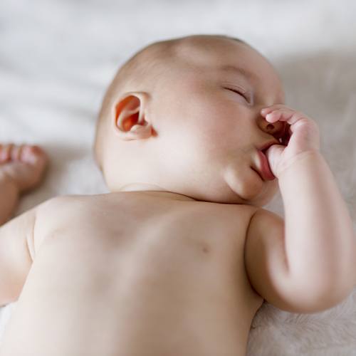 Infant sucking thumb in crib