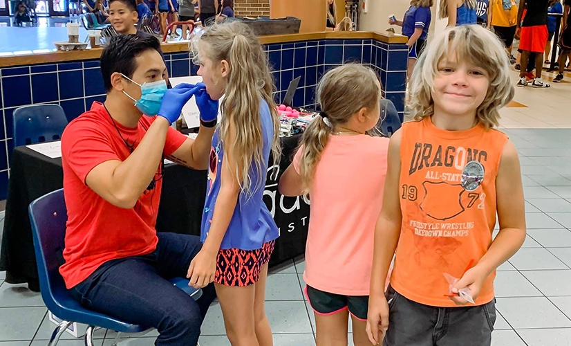 Dr. Nguyen examining you girl's teeth at community event