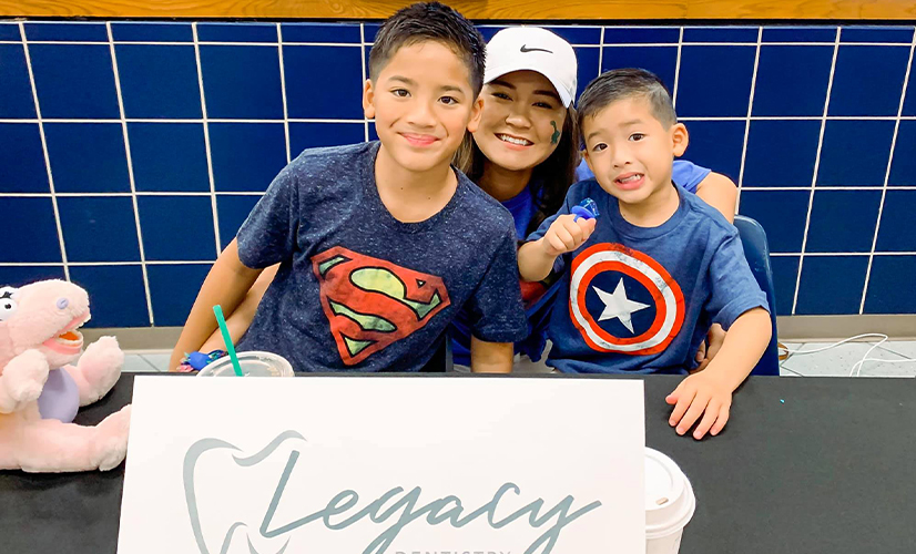 Team member and two kids smiling at community event