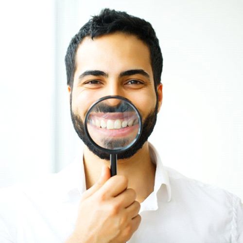 man showing off his smile with a magnifying glass