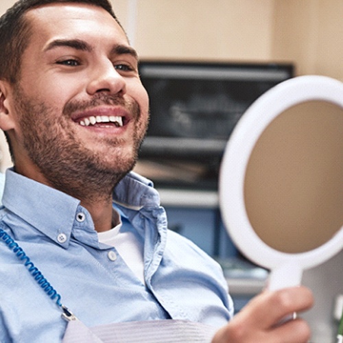 Dental patient admiring smile after receiving dental crown