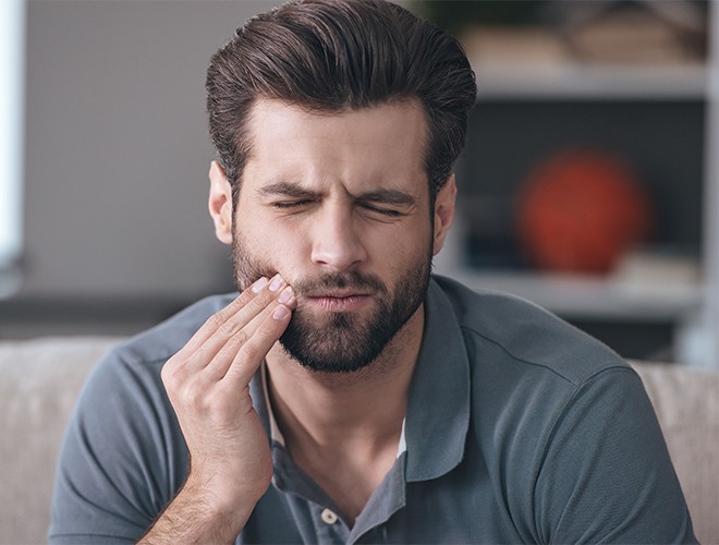 Man in need of emergency dentistry holding jaw