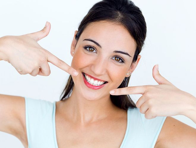 woman pointing to her smile after getting tooth-colored fillings in Midlothian 