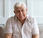 Senior man sitting on couch with dental implants in Midlothian, TX