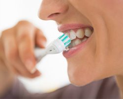 A woman brushing her teeth for dental implant care in Midlothian