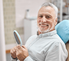 a man smiling while sitting at the dentist’s office