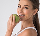 woman biting into a green apple 