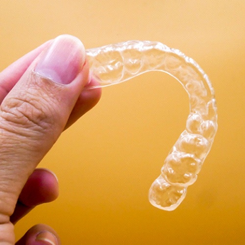 person holding their Invisalign aligners in their hand