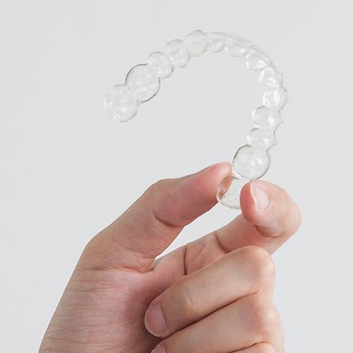 Hand holding Invisalign tray