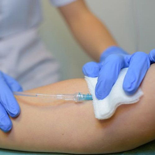Gloved hands placing IV in patient’s arm