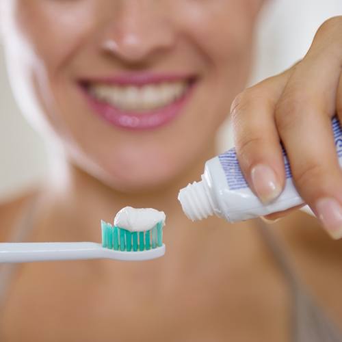 Woman putting toothpaste on toothbrush