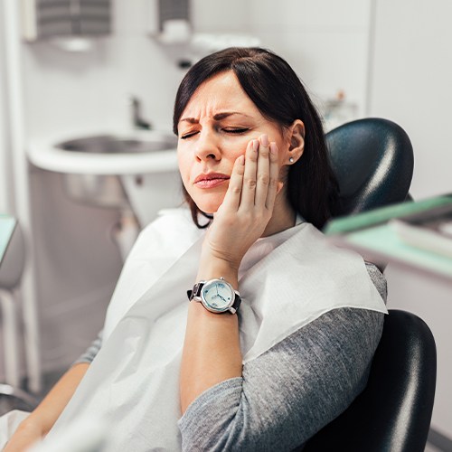 Woman in need of root canal therapy holding jaw