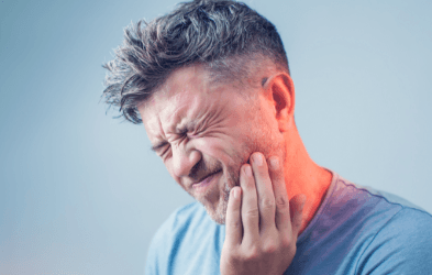 Man in need of restorative dentistry holding jaw