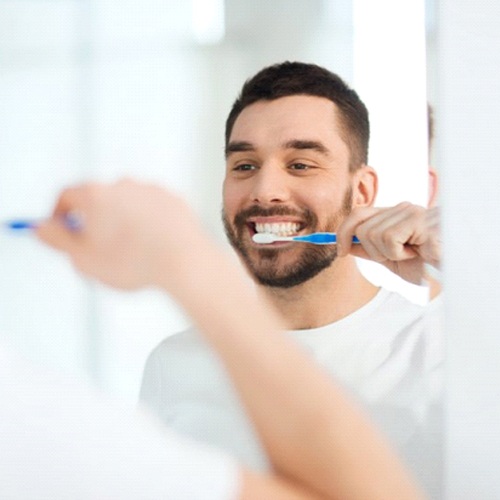 man brushing his teeth in front of a bathroom mirror