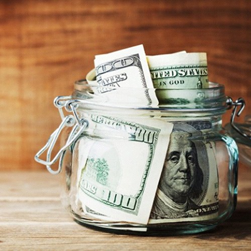 A jar full of money on a wood surface