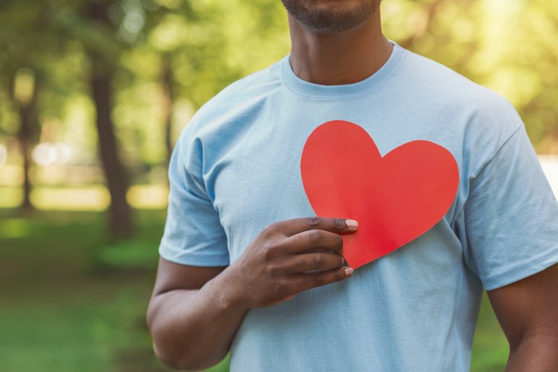 man holding paper heart over shirt