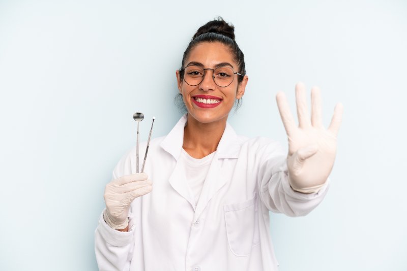 a dentist smiling and holding up four fingers