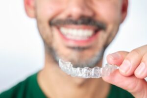 Man smiling while holding up his Invisalign